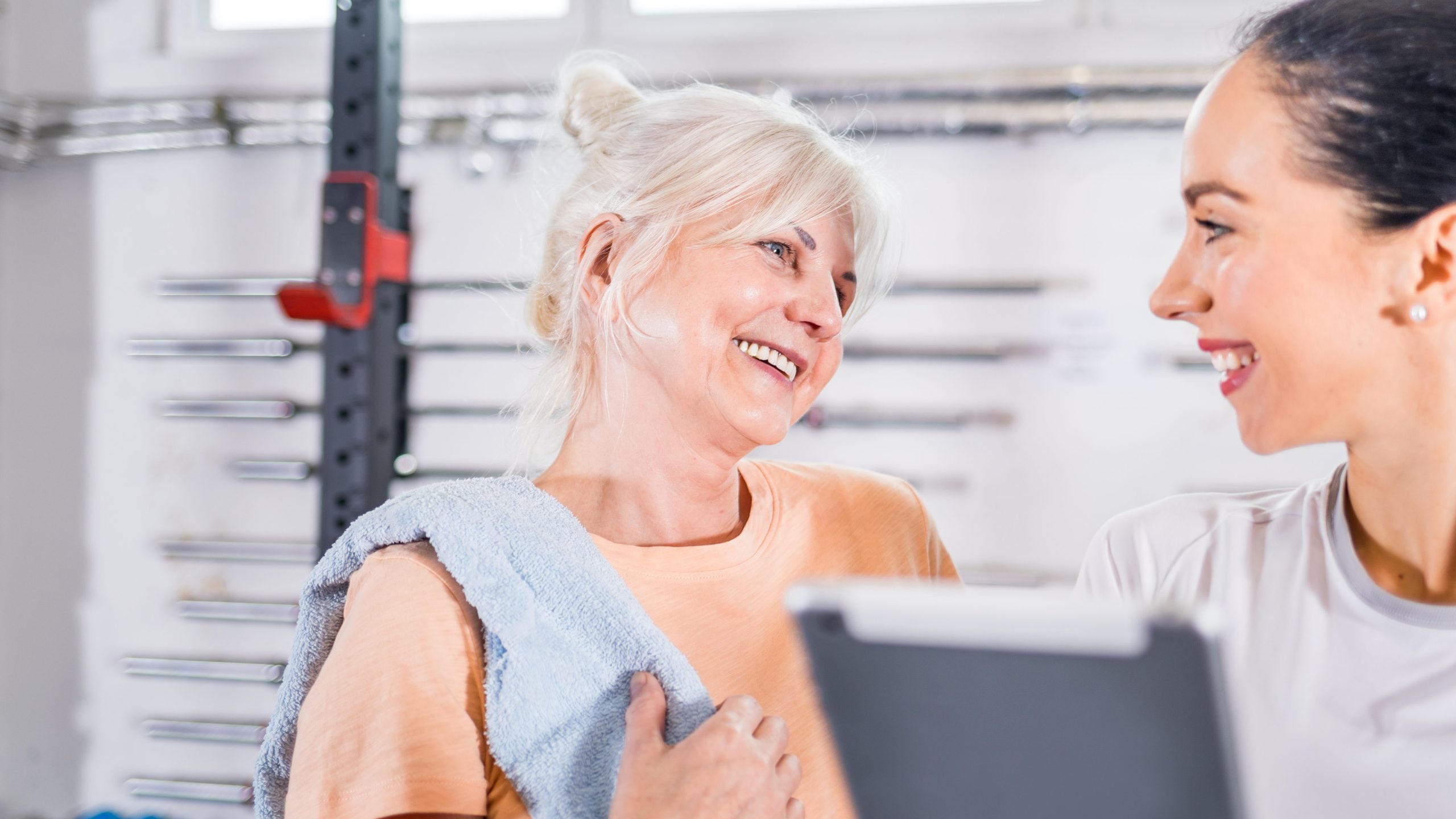 Früheren Ruhestand vorbereiten: Trainer arbeitet mit Seniorin im Fitnessstudio per Tablet